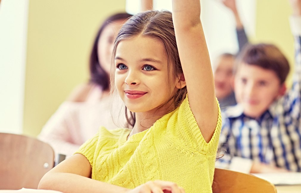 girl in classroom raising the hand 