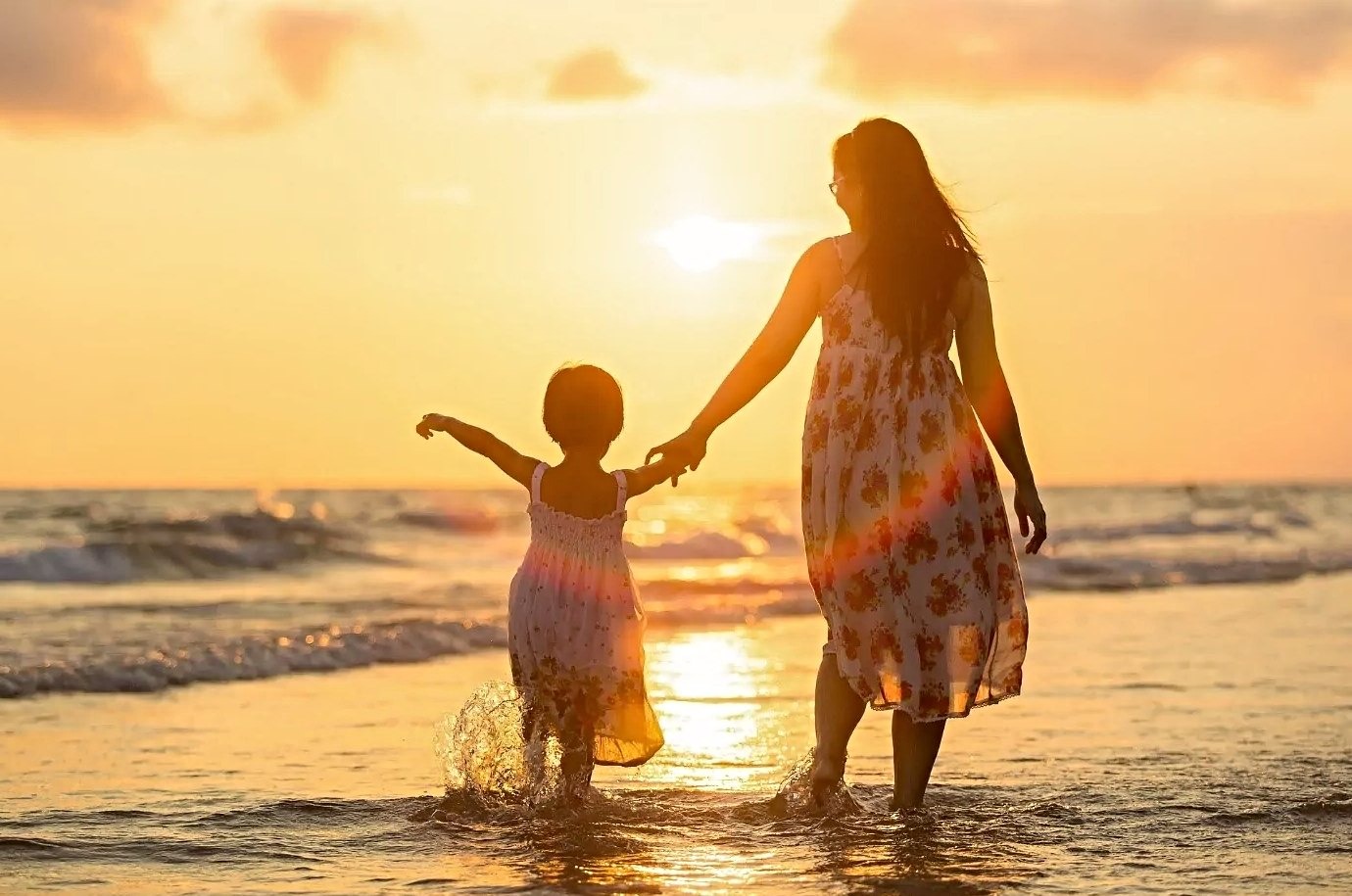 Mother and child are on a beach at sunset time