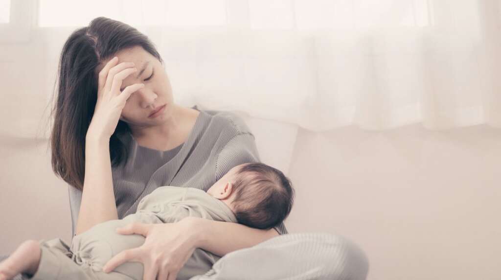 mother is feeding the baby while feeling anxious