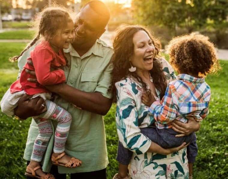 The family is laughing and enjoying themselves in the park. The most effective parenting styles.