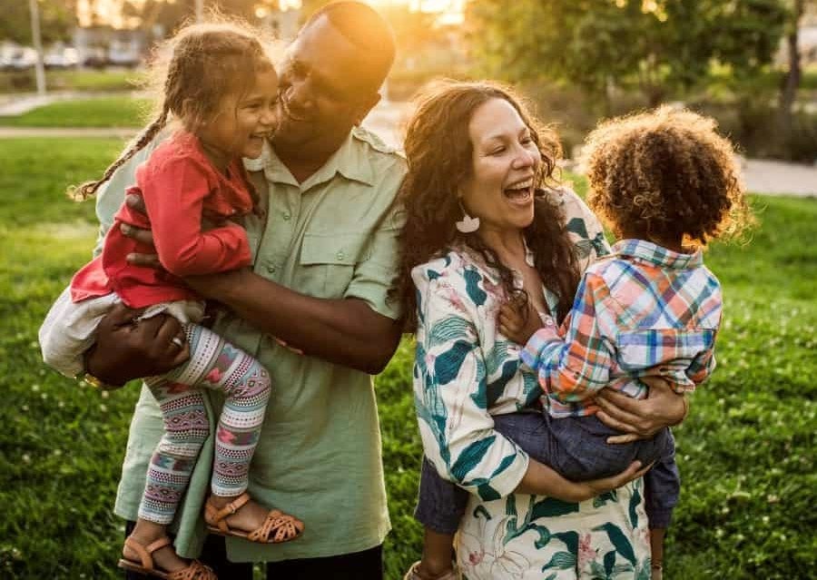 The family is laughing and enjoying themselves in the park. The most effective parenting styles.