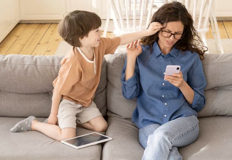 The mother is ignoring the child and using a mobile phone. It shows a neglected parenting style