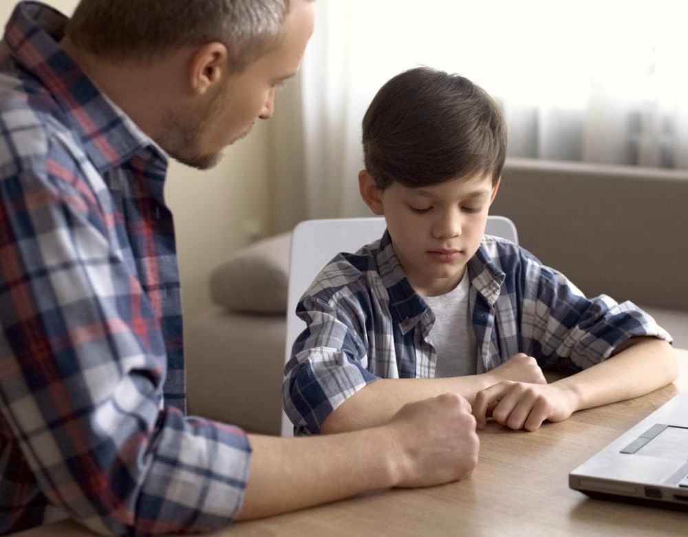 father is saying something to his son and the son is listening.