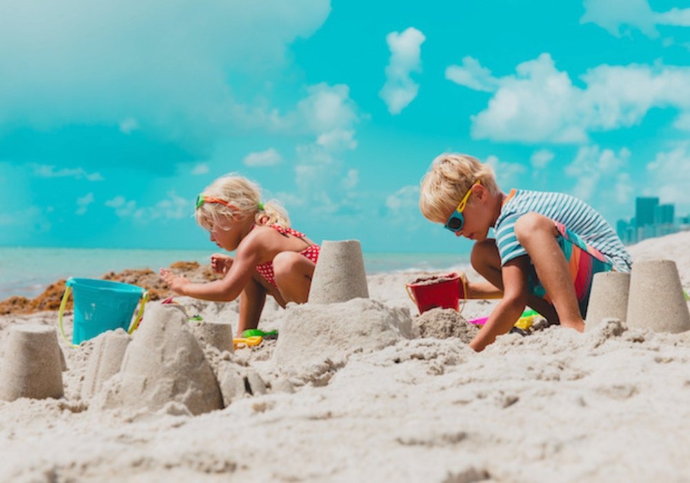 toddlers are playing with sand on beach and making a sandcastle. Outdoor activities for toddlers