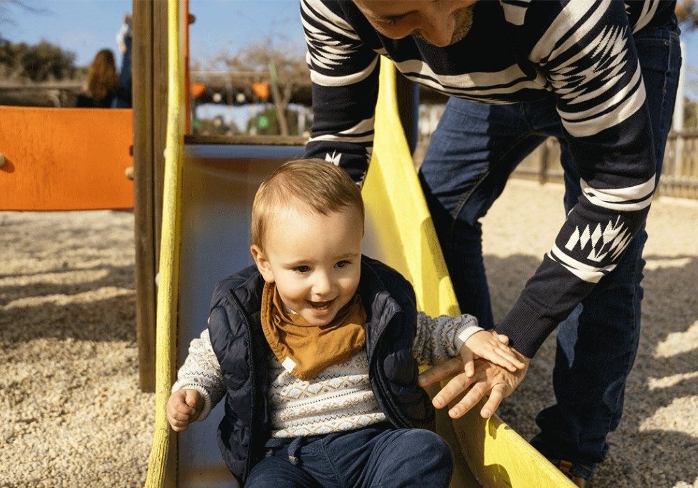 toddlers is taking a slide and laughing
