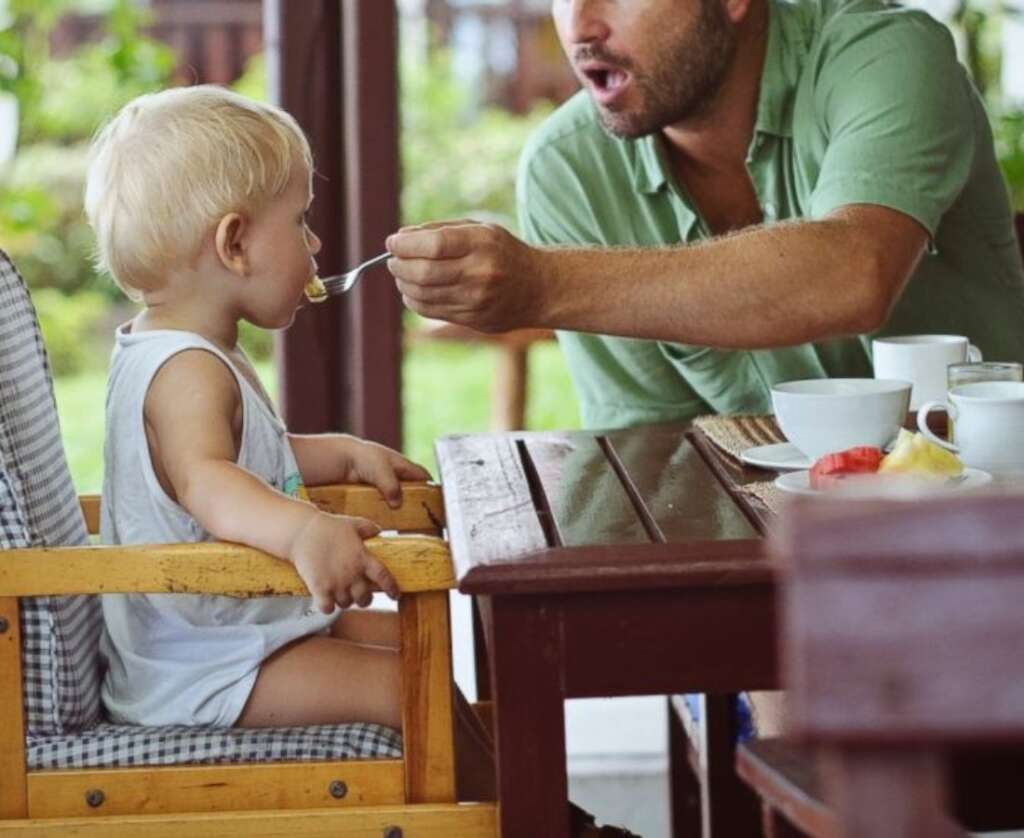 father is feeding baby with spoon